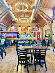 Inside a rustic dining hall at Trees Ranch in Zion National Park, warm wood beams frame a cozy restaurant setting.