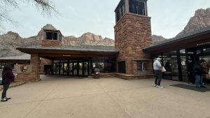Zion Canyon Visitor Center at Zion National Park with red rock cliffs forming a dramatic background.