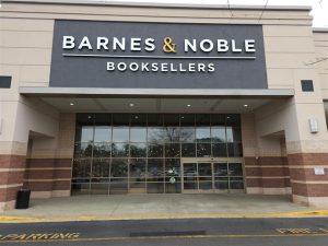 Exterior of a booksellers storefront with large glass doors and neutral tan brickwork.