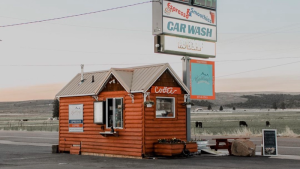 Small wooden coffee shack beside a highway sign at Bryce Canyon National Park, Utah, offering quick drinks near the park entrance.