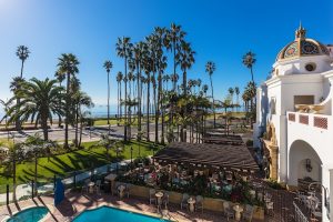 Seaside view from Santa Barbara Inn in Channel Islands National Park, with palm trees, a white domed building, and a blue ocean beyond.