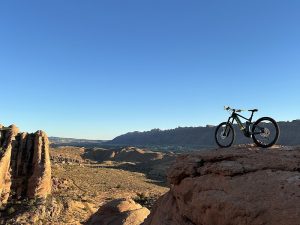 Mountain bike on a rocky ledge overlooks a desert canyon and sandstone formations in Arches National Park.