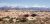 Sand flats with arched rock formations and scattered shrubs stretch toward snow‑capped mountains in Arches National Park.