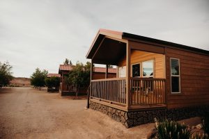 Wooden lodging cabins with porches line a dusty road at Capitol Reef National Park's campground area.