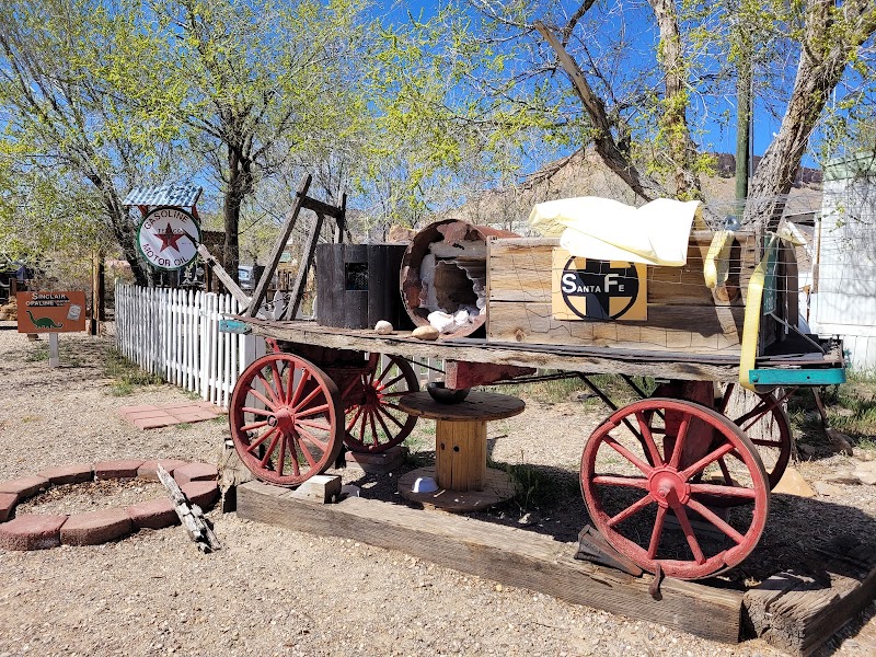 Old wooden wagon with red-spoked wheels sits on a trailer beside a weathered shed at Thompson Springs, Arches National Park.