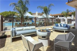 Poolside lounge and fire pit at a beachfront resort near Channel Islands National Park, with palm trees and a clear blue sky.