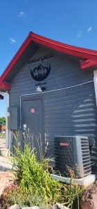 Cafe exterior at Capitol Reef National Park with gray siding, red trim, and a pine-tree logo sign.