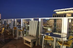 Rooftop hotel terrace with glass railings and city lights, viewed from a lodging near Congaree National Park.