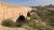 Stone arch bridge spans a dry riverbed near the town setting at Carlsbad Caverns National Park.