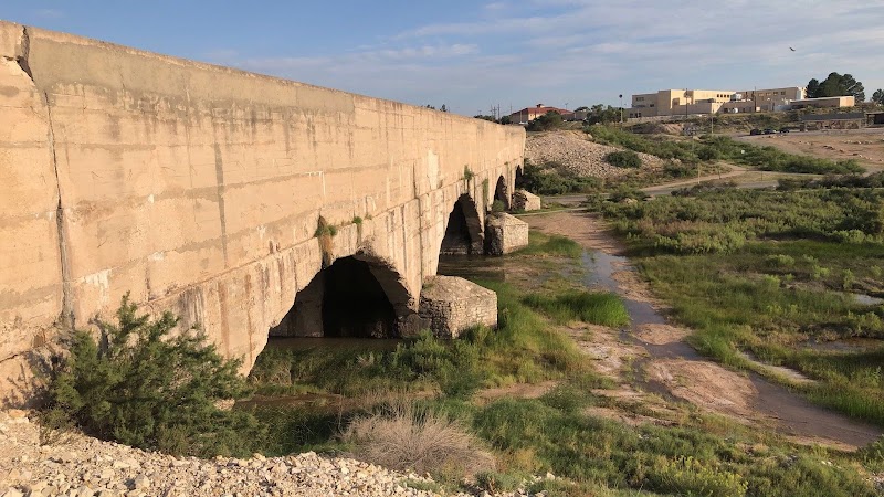 Stone arch bridge spans a dry riverbed near the town setting at Carlsbad Caverns National Park.