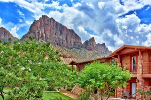 Cable Mountain Lodge exterior against red rock cliffs in Zion National Park with balconies and desert landscaping.