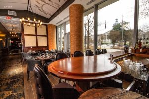 Interior of a polished Columbia steakhouse dining room with a curved wooden bar and large windows.