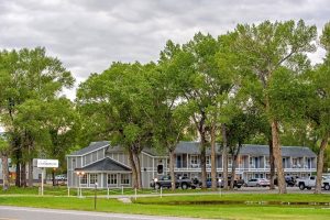 Lodge complex along Dos Rios with tall cottonwood trees and a gravel lot near Black Canyon of the Gunnison NP.