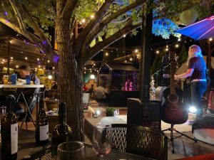 Outdoor restaurant patio in Carlsbad Caverns National Park, lit by string lights with guests dining under a tree.
