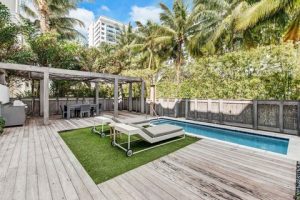 Pool deck with lounge chairs and a rectangular pool at a Biscayne National Park lodging, framed by palm trees and a shaded cabana area.