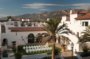 Hotel Californian courtyard at Channel Islands National Park with white stucco walls, red-tiled roofs, and palm trees against distant mountains.