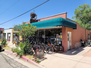 Peach-colored shop with a teal awning in Arches National Park, bikes lined in racks outside and a storefront full of gear.