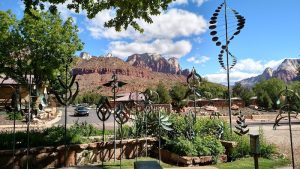 Worthington Gallery in Zion National Park features metal sculptures with red rock cliffs behind.