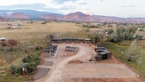 Lodging casitas clustered along a dirt driveway with red rock cliffs surrounding Capitol Reef National Park.