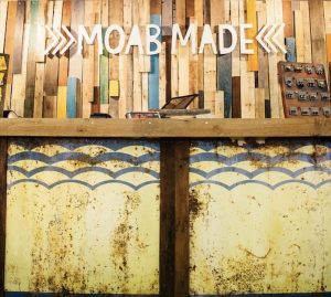 Inside Arches National Park gift shop: rustic wooden walls with colorful planks, a counter, and a blue scalloped panel.