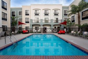 Pool area at Santa Barbara/Goleta lodging near Channel Islands National Park, with red seating and umbrellas.