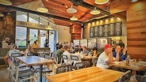 Interior dining hall inside Zion National Park restaurant, with wood paneling, communal tables, and visitors dining.