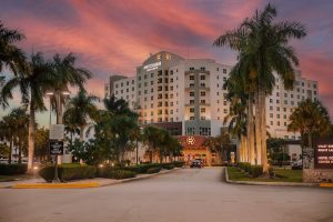 Exterior of a large resort near Biscayne National Park at sunset, palm-lined entrance and pastel sky.