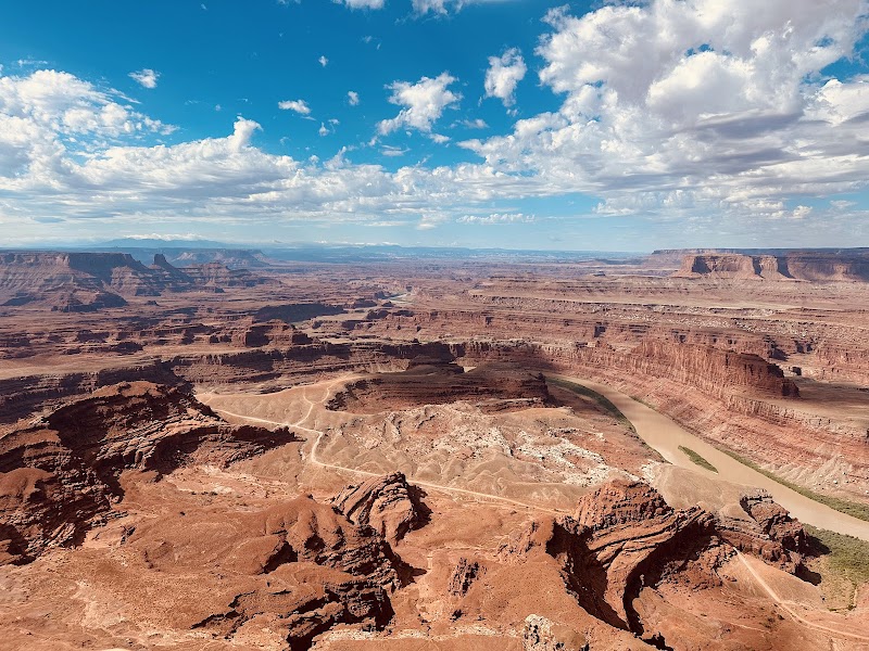 Vast red rock canyon and layered mesas overlook a winding river at Dead Horse Point in Arches National Park, Utah.