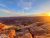 Sunset over layered sandstone cliffs and a winding river at Dead Horse Point in Arches National Park, with warm orange rock and blue sky.