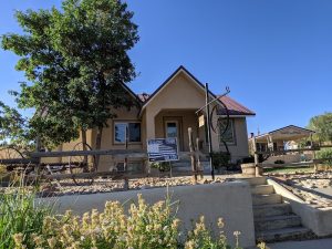 Rustic lodge-style lodging near Capitol Reef National Park with a fenced yard and a large tree.