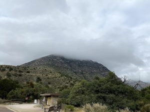 Pine Springs Trailhead at Carlsbad Caverns National Park sits at the northern entrance with rocky hills and a cloudy sky.
