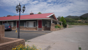 Motel exterior near Black Canyon Of The Gunnison National Park with a red roof, adjacent parking, and a stone facade.