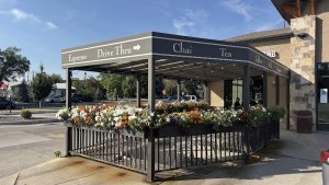 Drive-thru coffee stand at Black Canyon Of The Gunnison National Park with a flower-filled patio and nearby storefront.