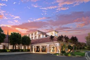 Lodging near Channel Islands National Park's coast with a welcoming hotel exterior, palm trees, and a colorful sunset sky.