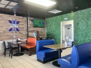 Interior dining area at Carlsbad Caverns National Park’s restaurant, featuring blue booth seating, a wooden accent wall, and a wall-mounted TV.