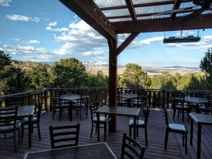 Outdoor dining deck at Bryce Canyon National Park with wooden furniture and canyon views beyond the railing.
