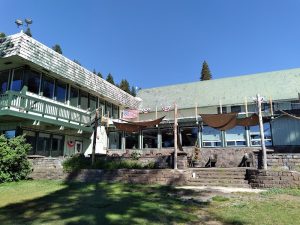 Diamond Lake Resort lodge at Crater Lake National Park, a lodge-style building with a green roof, deck, and stonework under a clear blue sky.