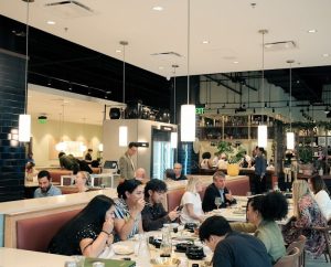 Diners fill a modern restaurant dining area with booth seating and pendant lights near Congaree National Park.