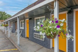 Lodging exterior at Black Canyon Of The Gunnison National Park with bright orange doors and hanging flower baskets along a covered walkway.
