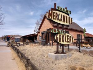 Rustic storefront along a gravel path in Capitol Reef National Park, with weathered signs and dry grasses.