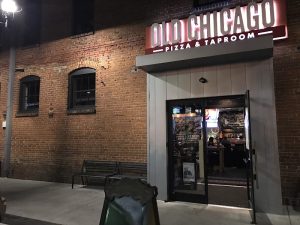 Night view of a brick restaurant exterior near Congaree National Park, with a lit sign and glass doors at street level.