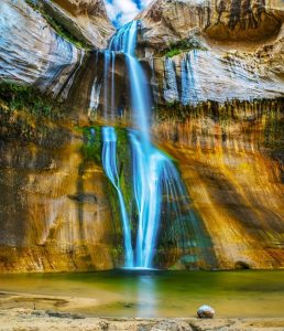 Lower Calf Creek Falls cascades over colorful canyon walls in Capitol Reef National Park, Utah.