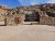 Stone entrance with a black Arches National Park sign and a National Park Service shield set against red cliff rocks.