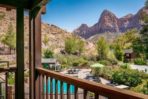 Pool deck at a Zion National Park lodge in Springdale, with red rock cliffs and blue sky.