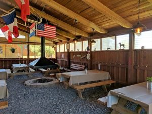 Outdoor dining area in Capitol Reef National Park with wooden beams, flags, and picnic tables.