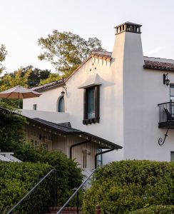 Exterior of a white stucco lodging building in Santa Barbara, with a tiled roof and greenery, associated with Channel Islands National Park.