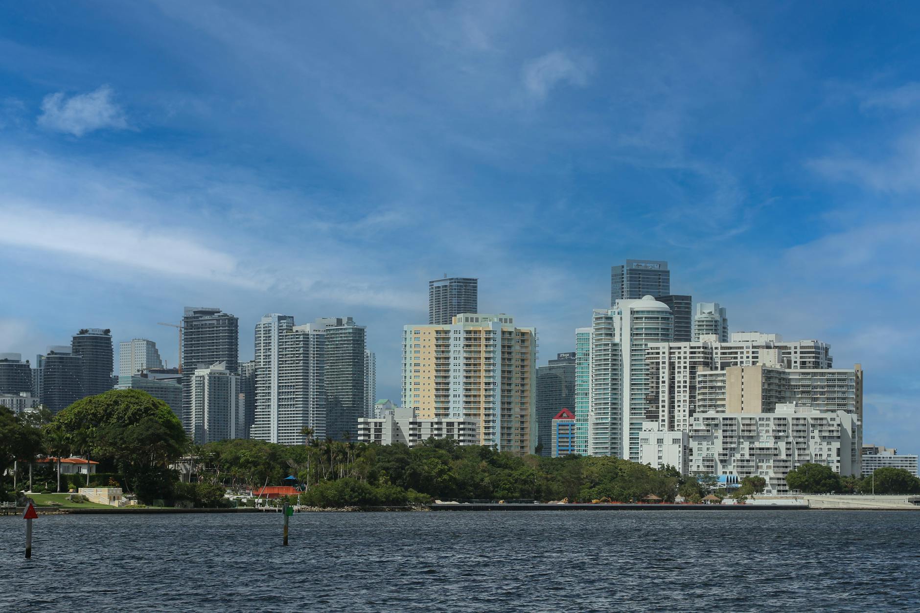 Stunning view of Miami's skyline over Biscayne Bay with clear skies and lush greenery.