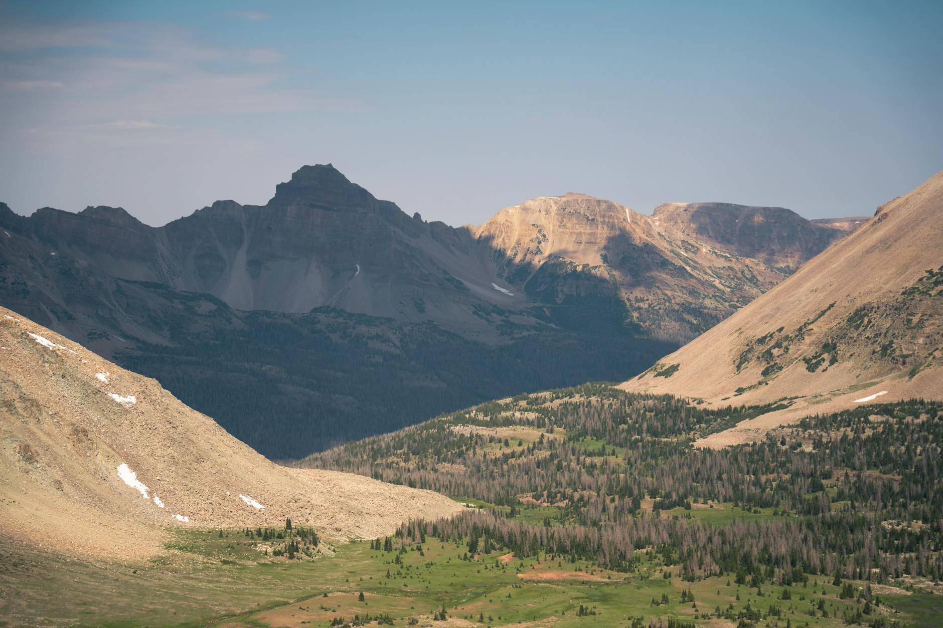 A breathtaking daytime view of the Uinta Mountains, showcasing a lush valley surrounded by rugged peaks.