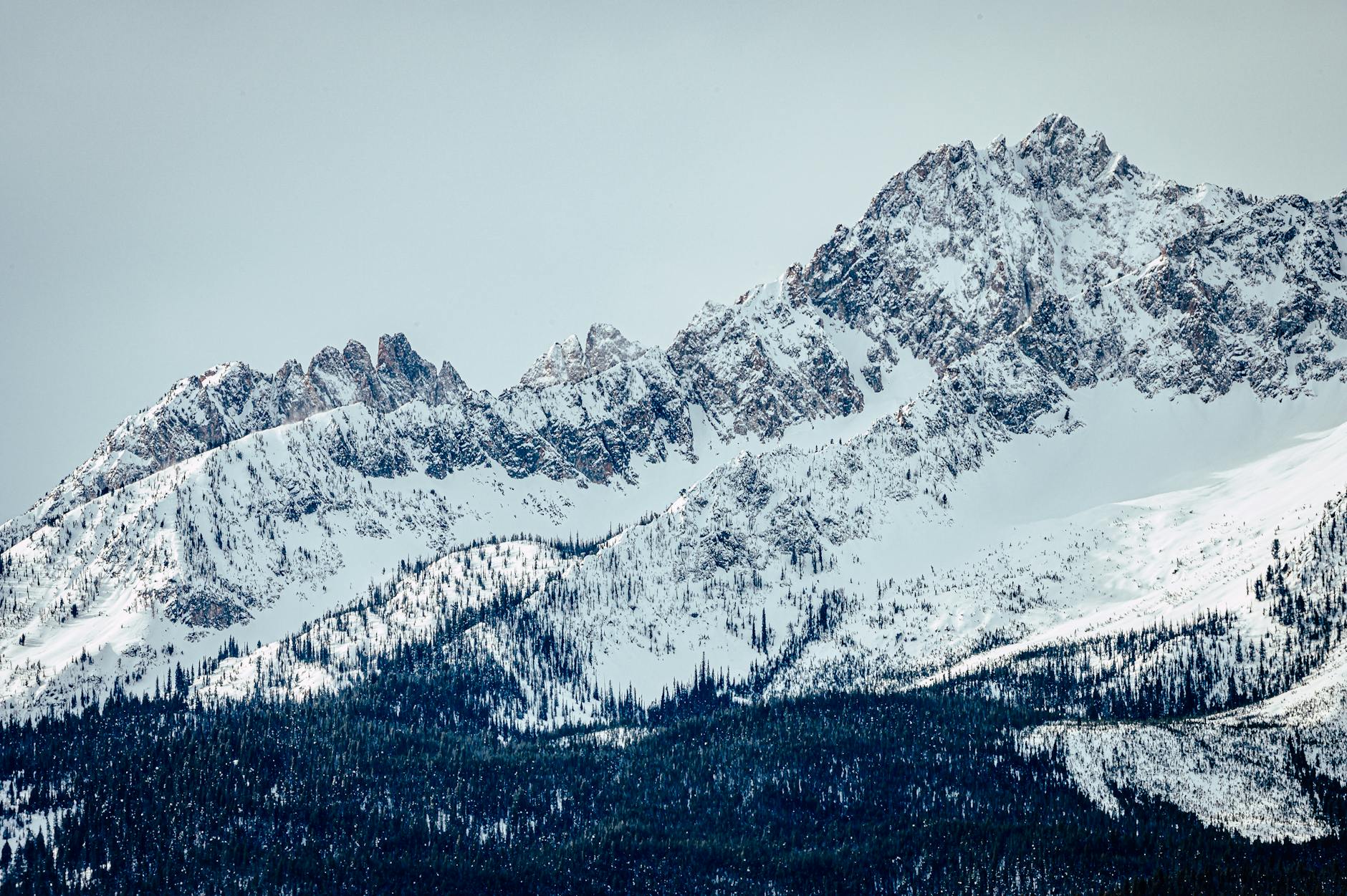 Breathtaking view of snow-capped mountain peaks under a clear sky, capturing the essence of winter's beauty.