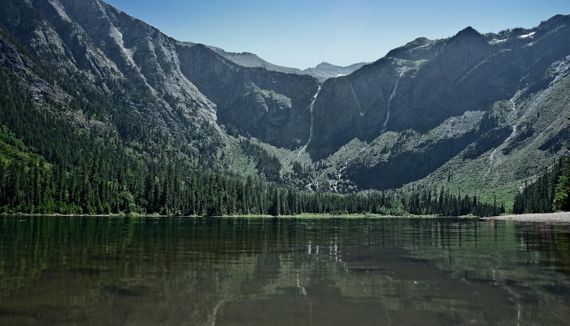 Stunning landscape of Avalanche Lake with mountain reflections and lush greenery in Montana.